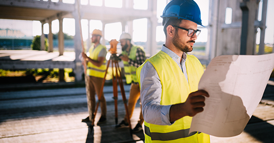 man on construction site looking at plans