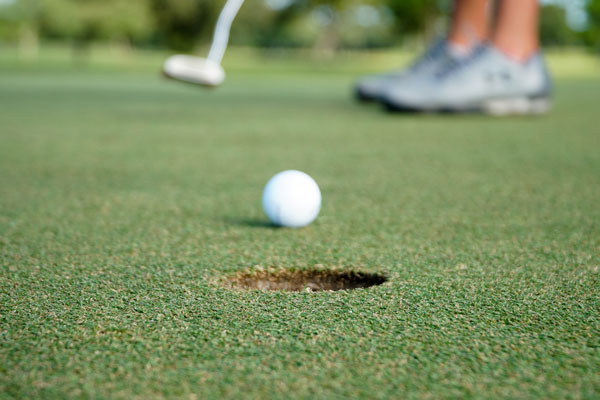 golf ball putt into hole