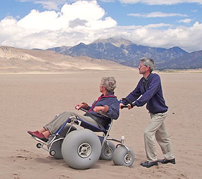 man pushing an accessible sand dune wheelchair in California