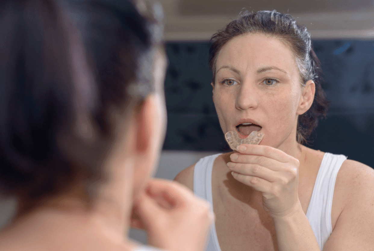 woman placing mouth guard in mouth