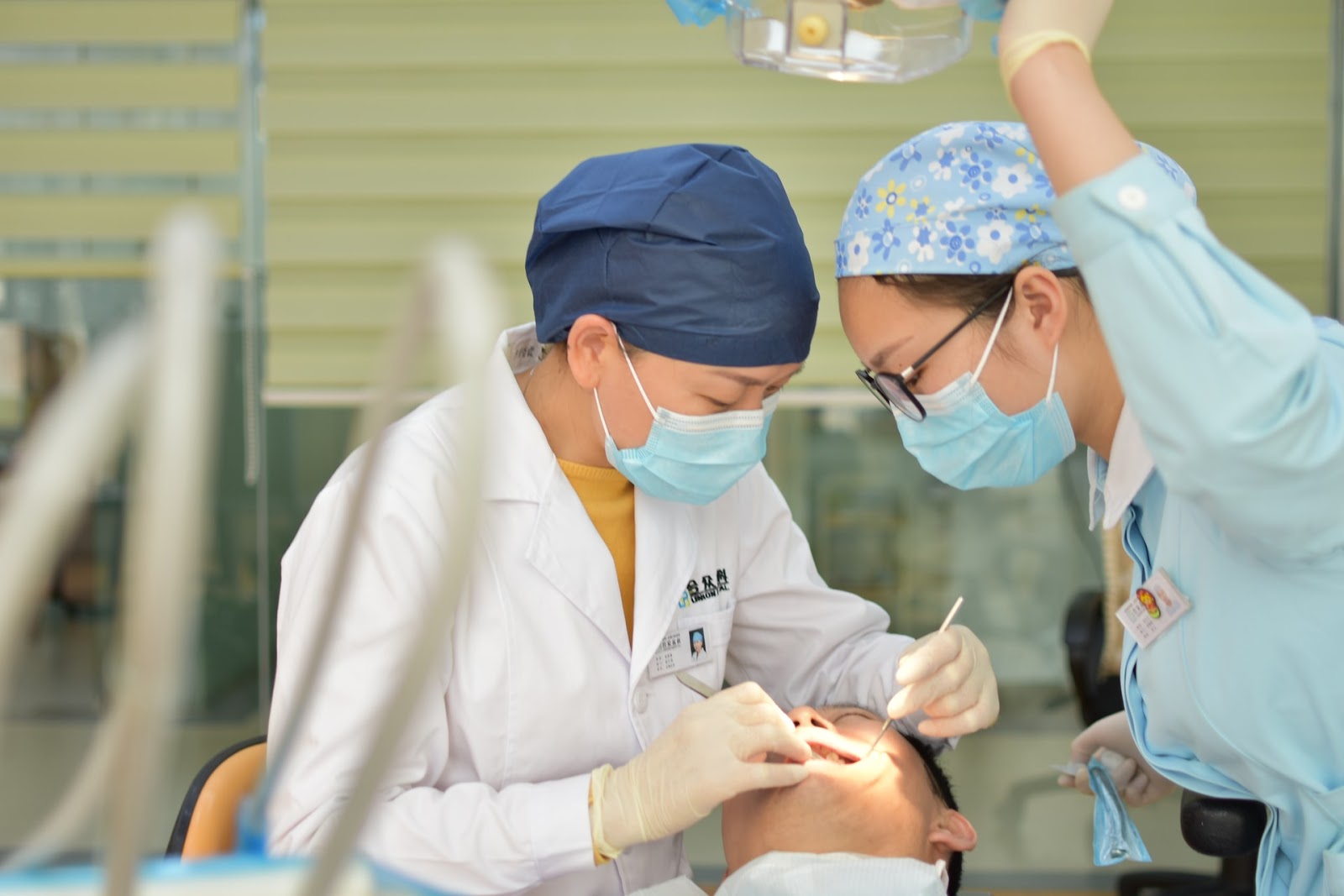 two female doctors checking one men teeth