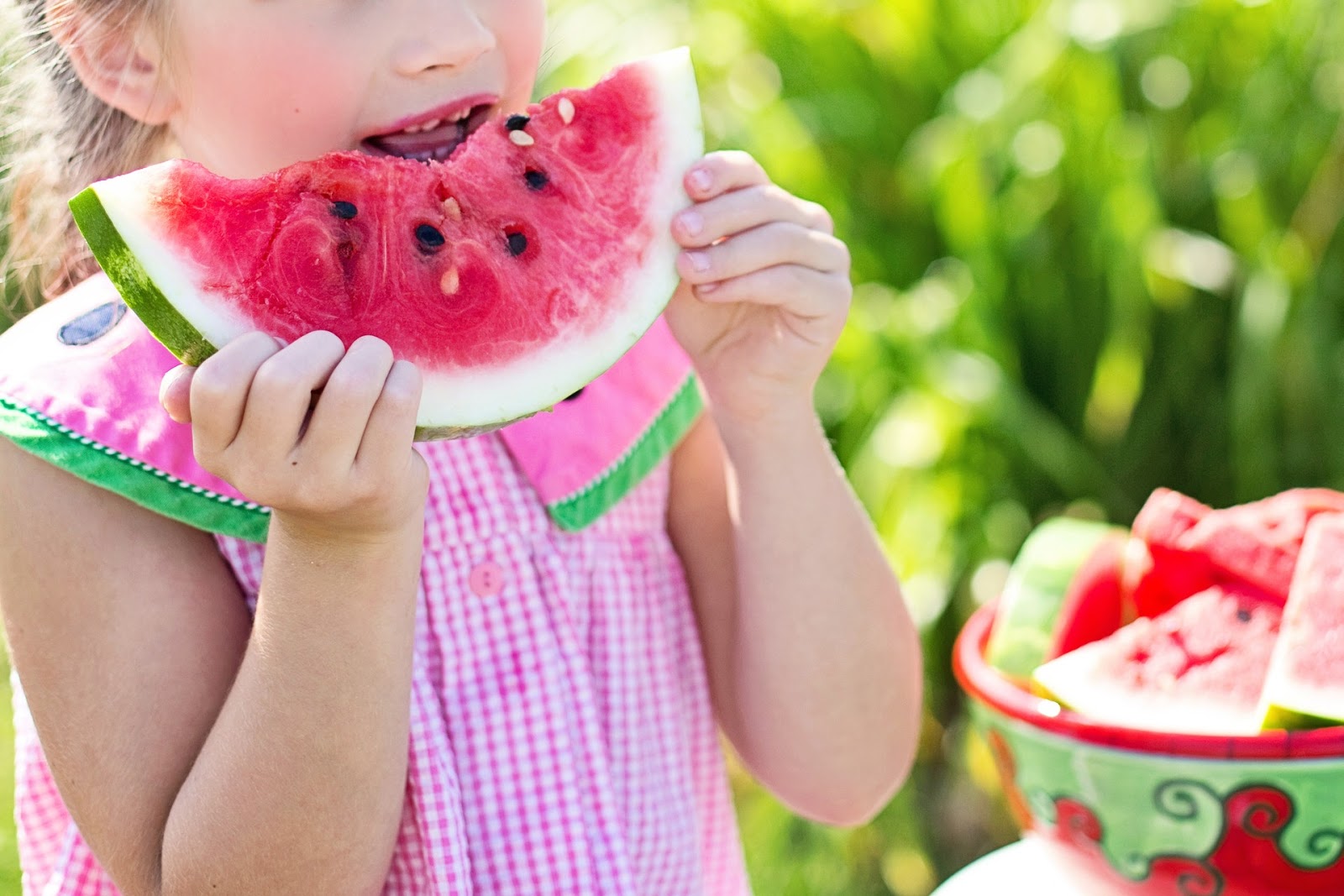young girl eating a piece of watermelon