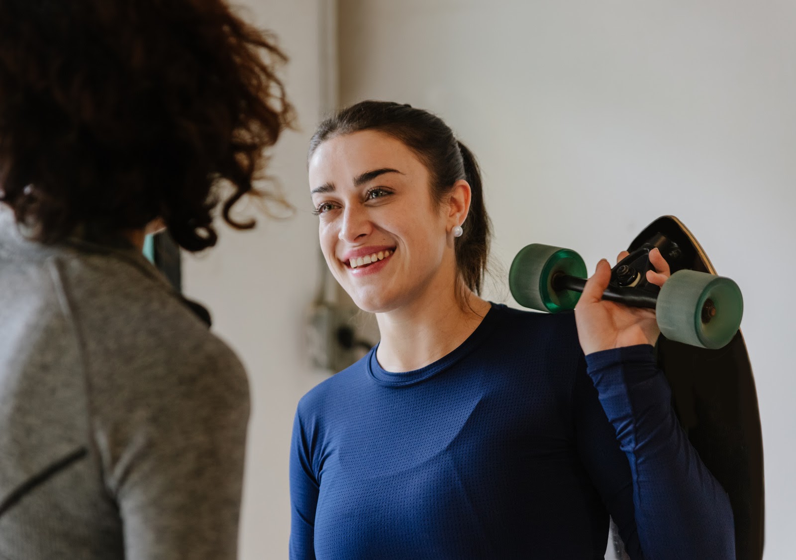 smiling woman in blue holding skateboard
