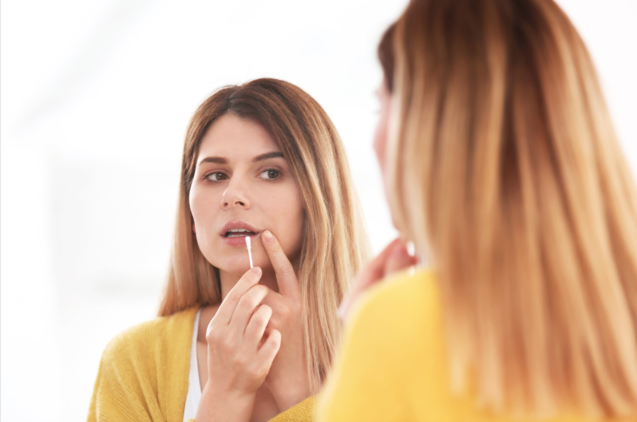 woman looking at her lips in the mirror