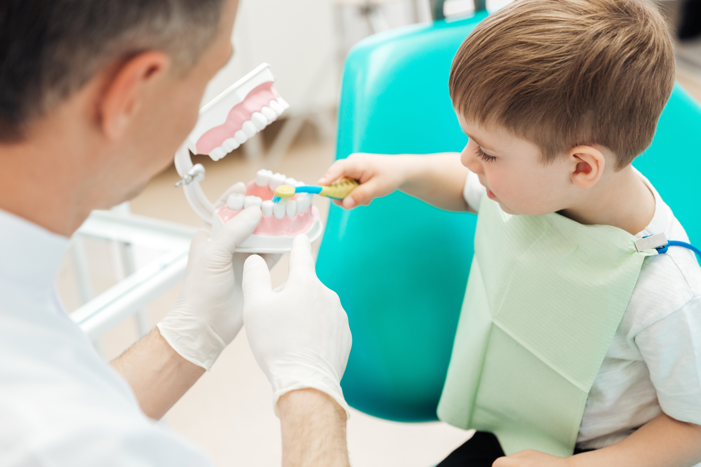 dentist showing little boy how to brush his teeth!