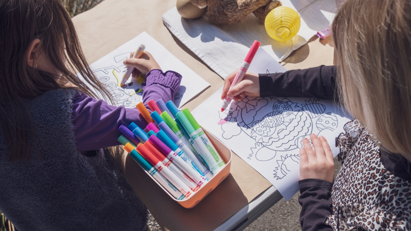 Girls coloring on table outside