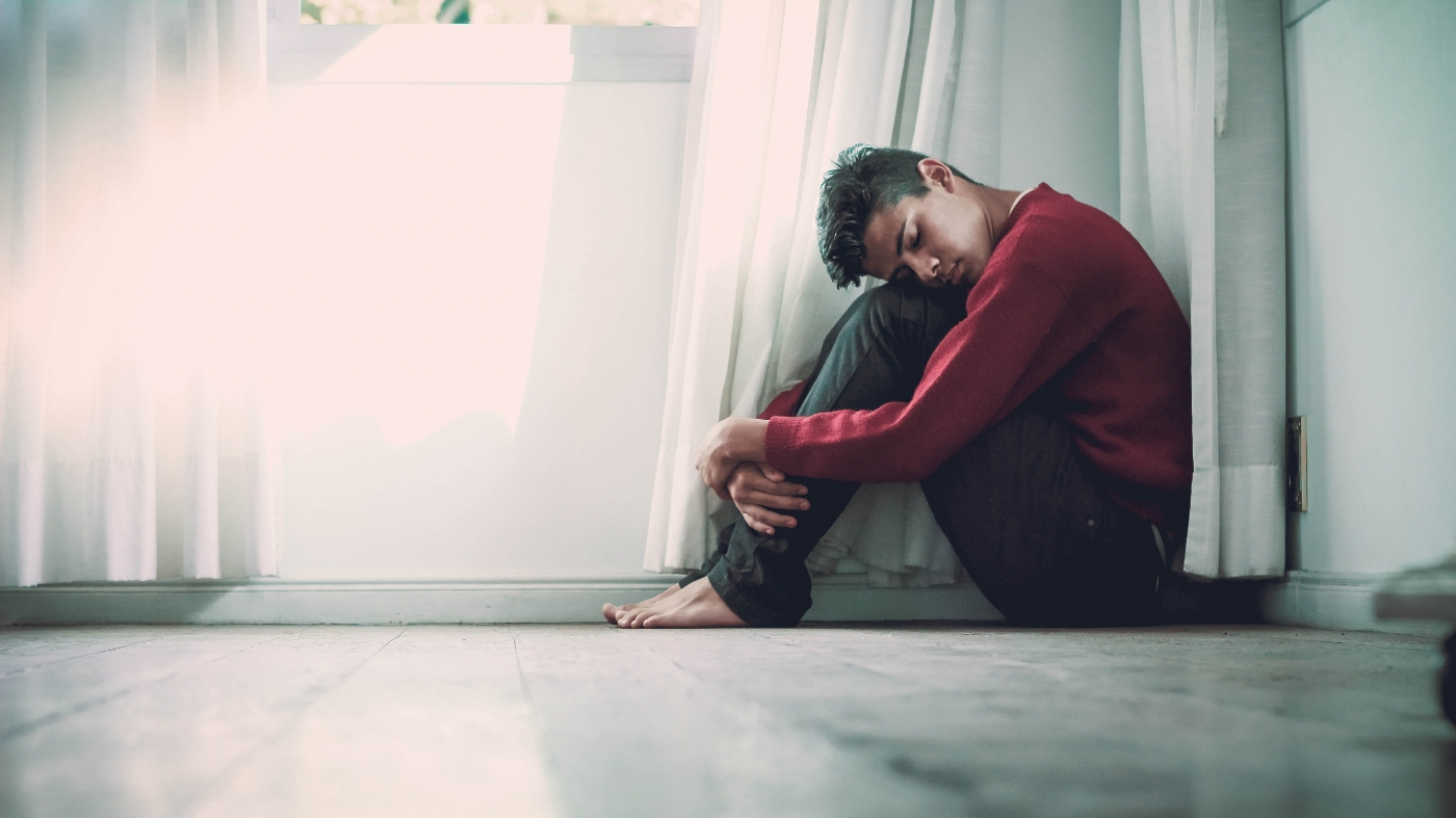 Scared man hugging his legs on the floor