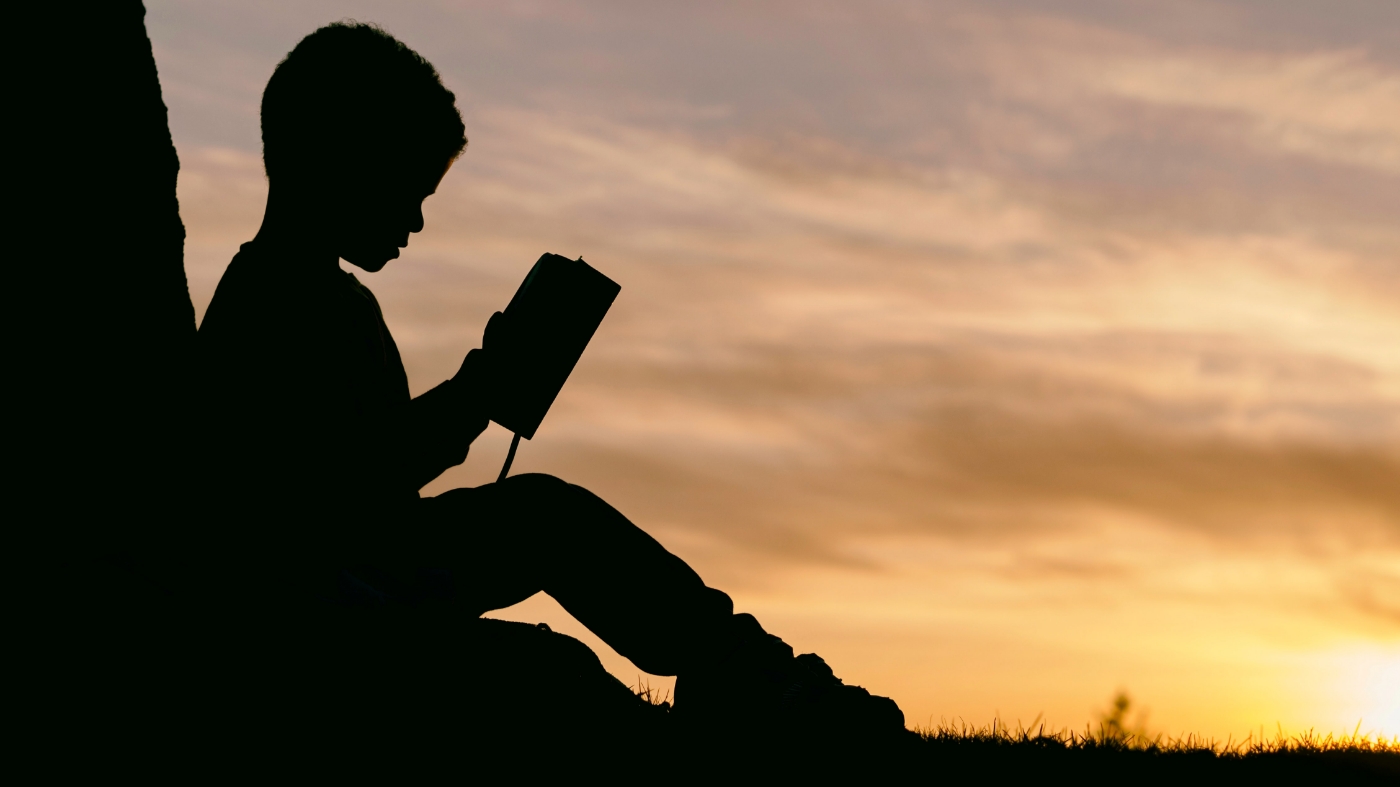 Boy reading bible outside