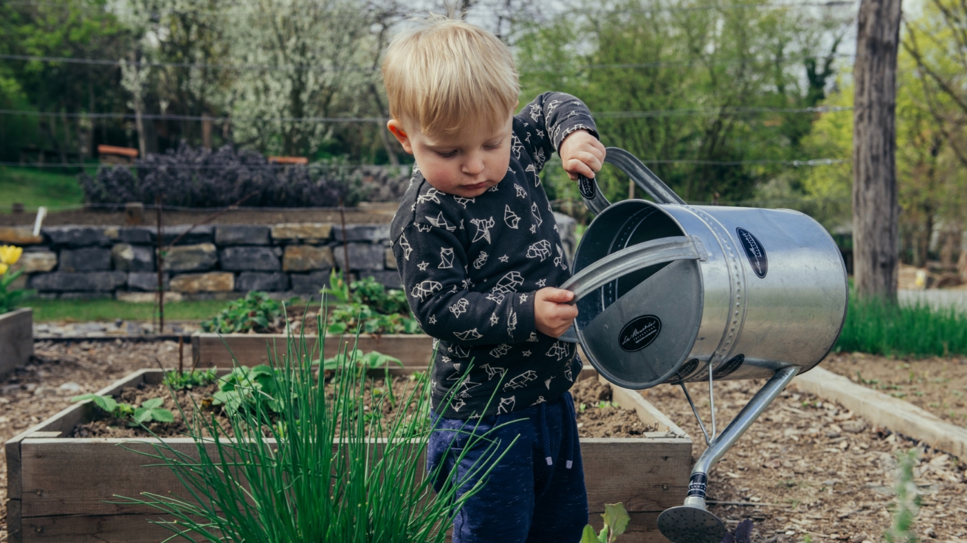Little kid helping water the plants
