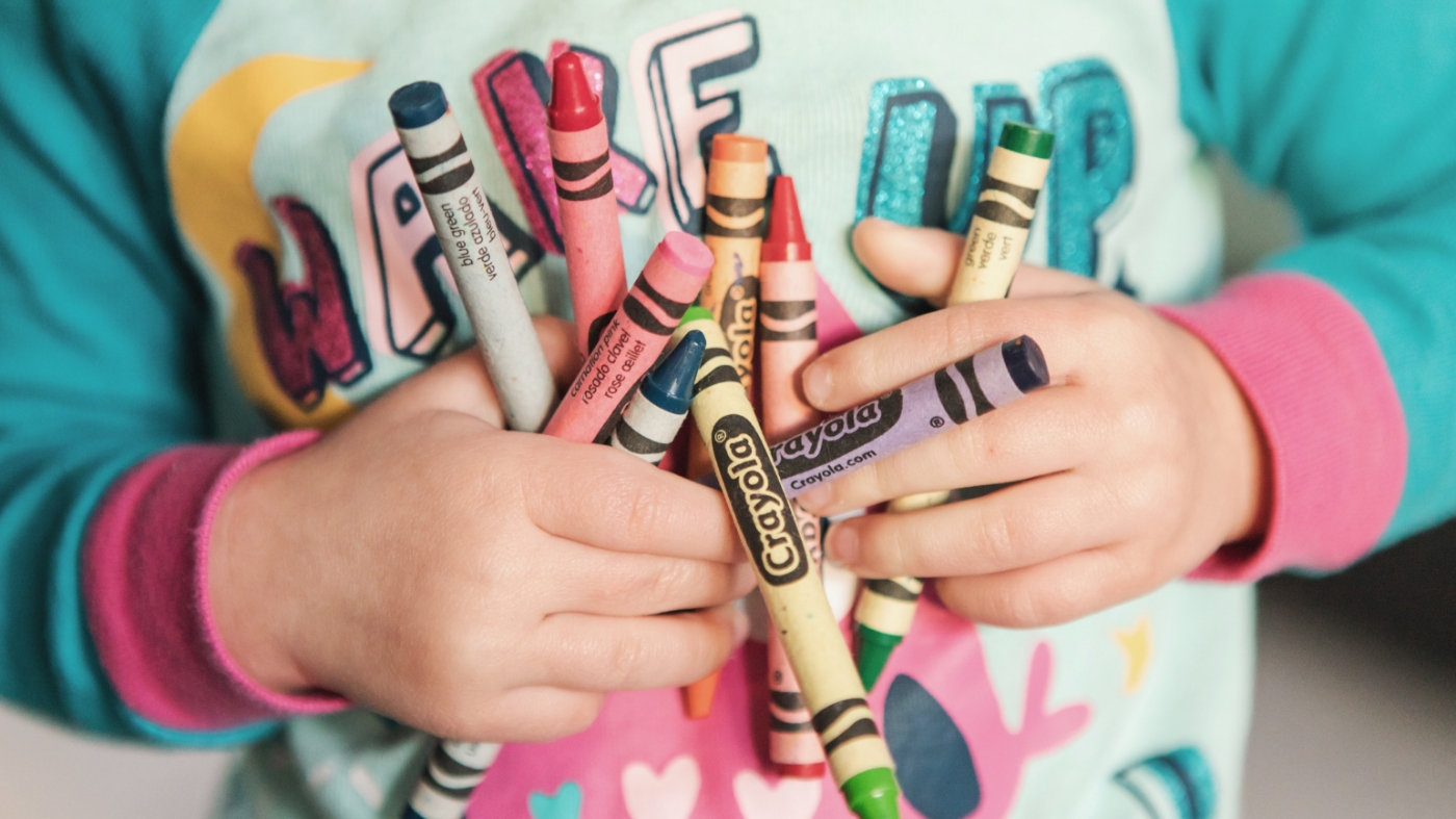 Young kid holding all the crayons in two hands