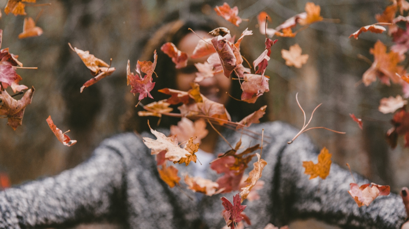 Woman tossing fall leaves in air