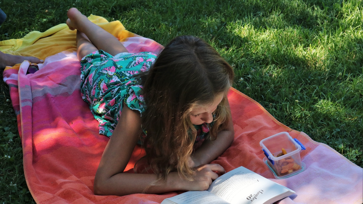 Young teen girl reading outside