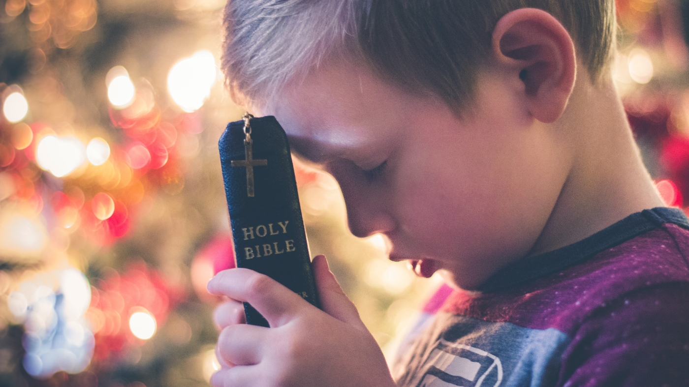 Kid holding bible having faith in God