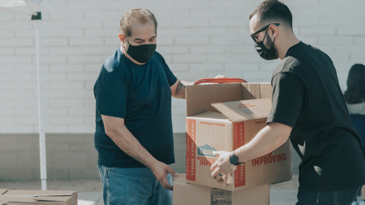 Two men unloading anonymous support boxes