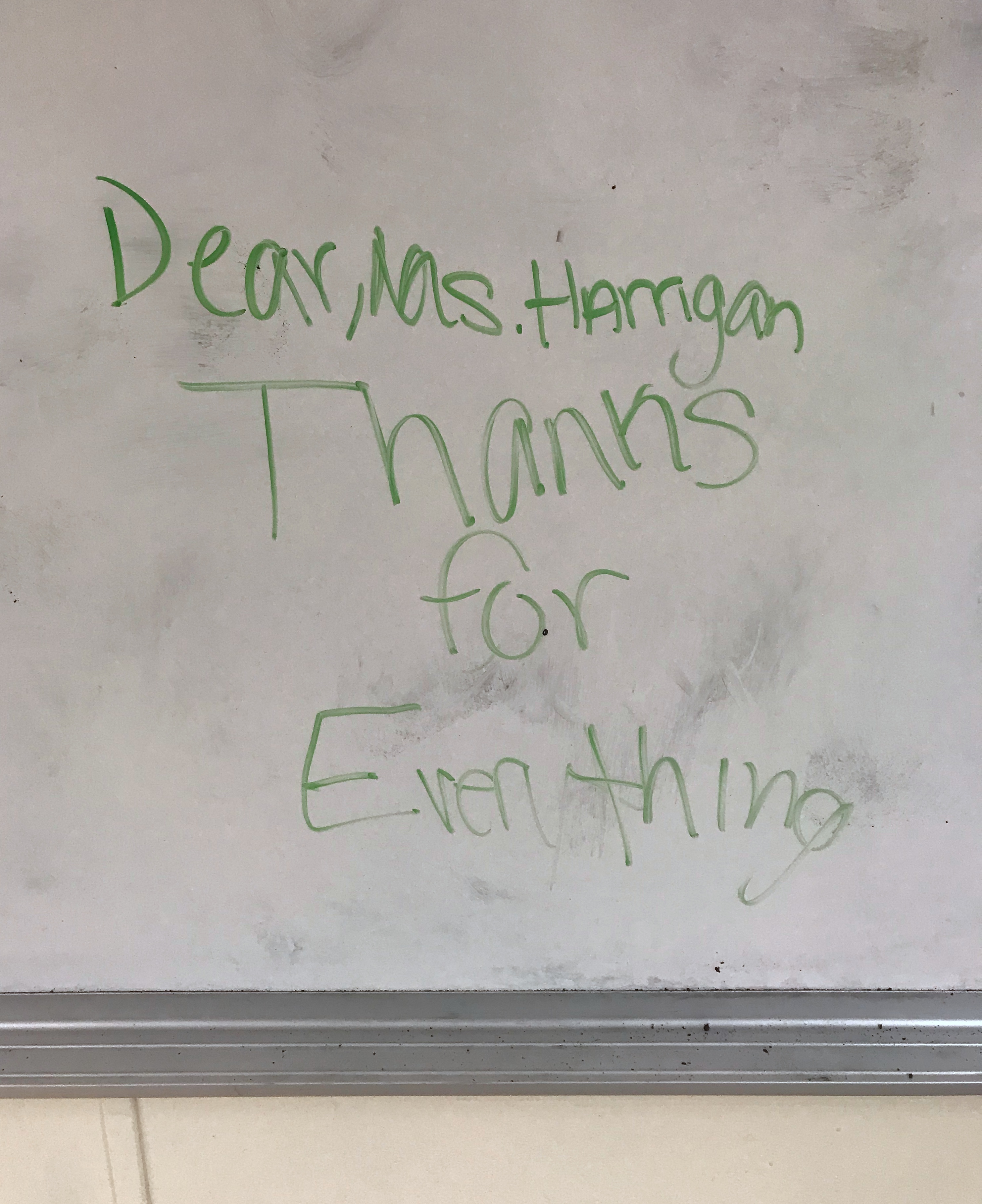 Writing on a very smudged whiteboard. It says“Dear, Ms. Harrigan Thanks for Everything”.