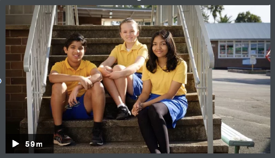 Image of three primary school aged children sitting on steps in a school yard.