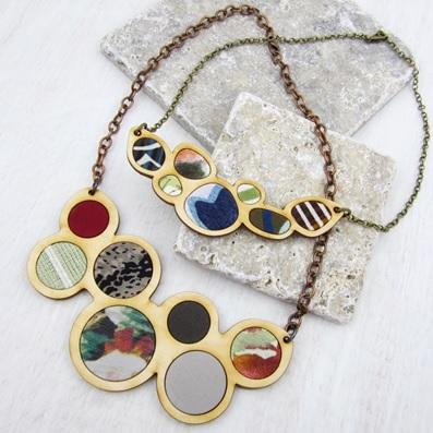 Completed wood necklace with various colors of fabric in-layed into wood.