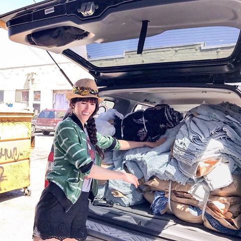 Alyssa standing by the trunk of her car which is packed full of bundles of fabric from L.A. clothing manufacturer