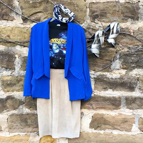 Flat lay: cobalt blue blazer, galaxy graphic tee, high waisted, suede, light beige skirt, criss-cross metallic, chunk heels, and blue and white Regenerous Designs headband