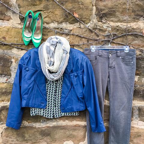 Flat lay: indigo leather jacket, black, white, and green checkered, button-down blouse, gray wash, striped jeans, green, pointed toe heels, and gray and white Regenerous Designs scarf.