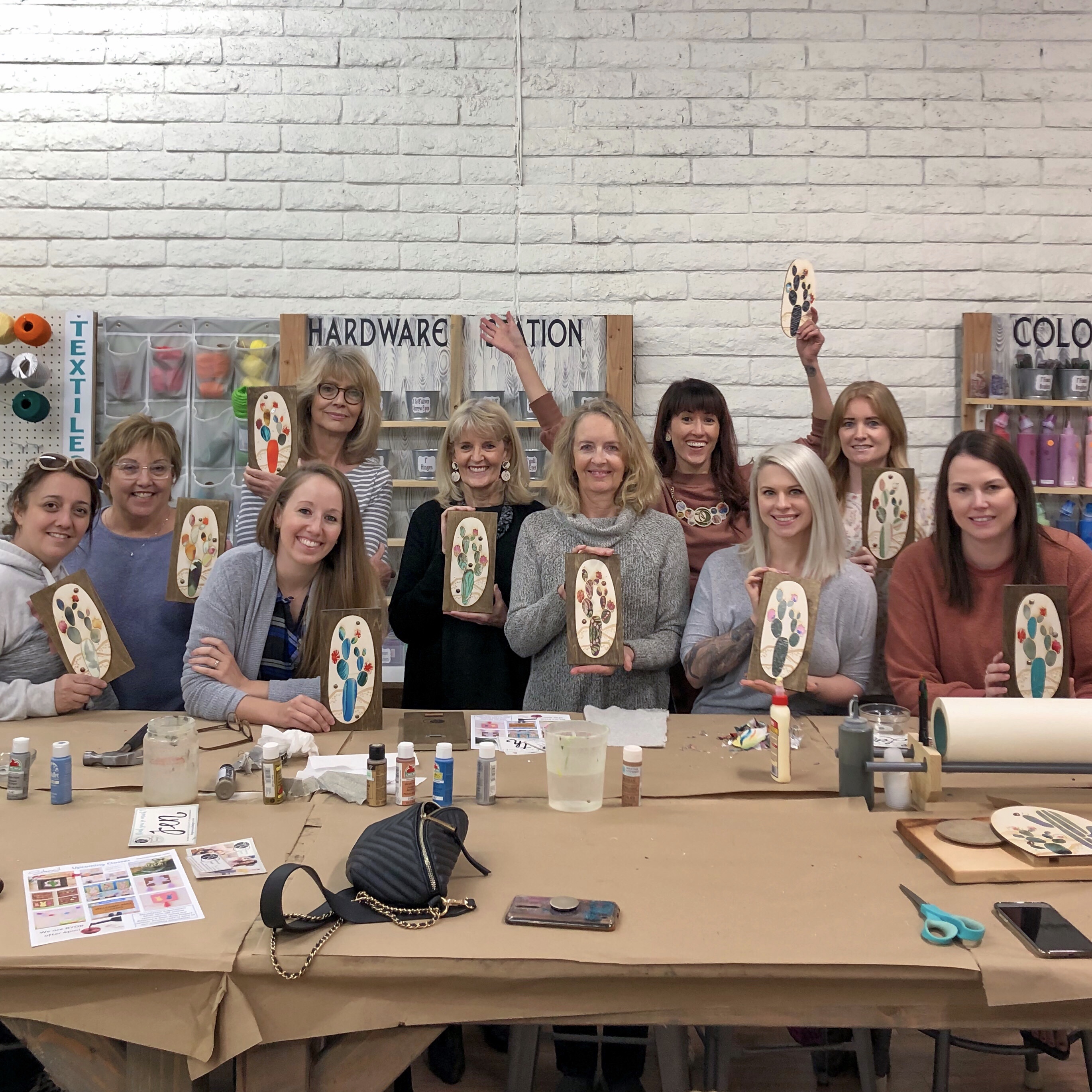 group of students at a DIY Art workshop at Stencil: A DIY Craft Studio holding textile and wood cactus art