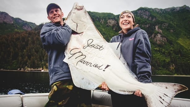 Newlyweds holding large halibut caught while charter fishing in Homer, Alaska with DeepStrike Sportfishing