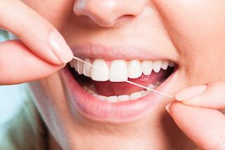 A woman flosses her teeth | Preventative Dentistry Dee Why NSW