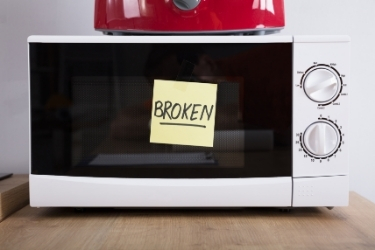 Microwave and a sticky note with the word "Broken"