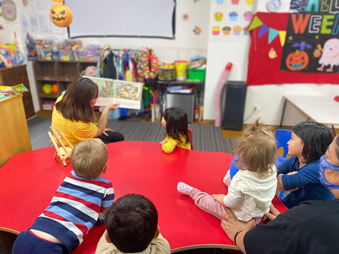 A teacher reading a book to children.