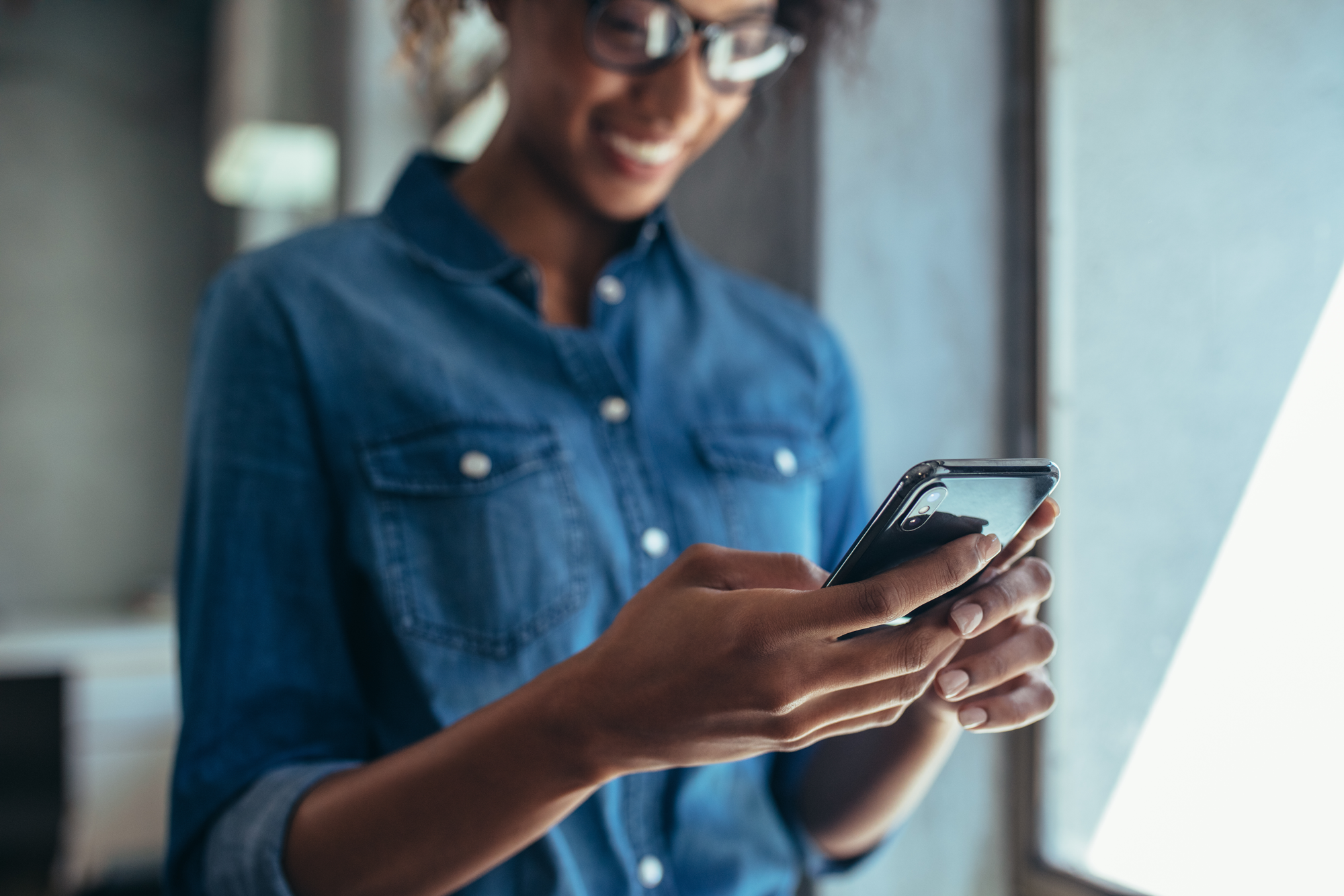 Frau mit Jeanshemd hält Smartphone