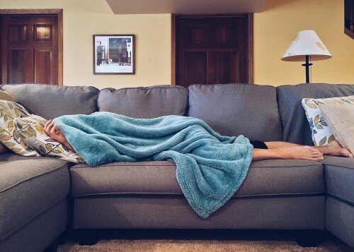 person laying on couch feeling ill