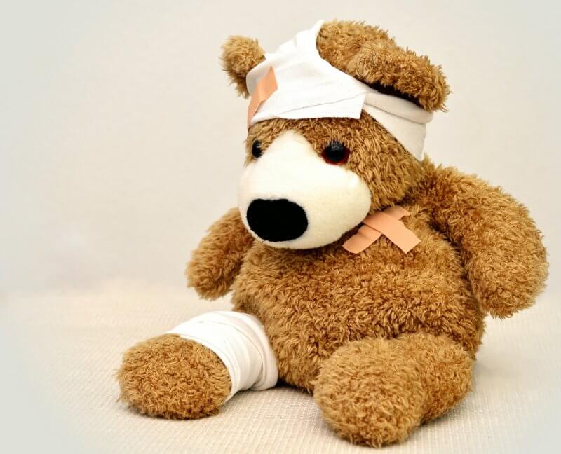 teddy bear with bandage on head and leg after getting treated in healthcare system