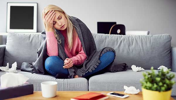 woman sitting on couch sick with covid-19