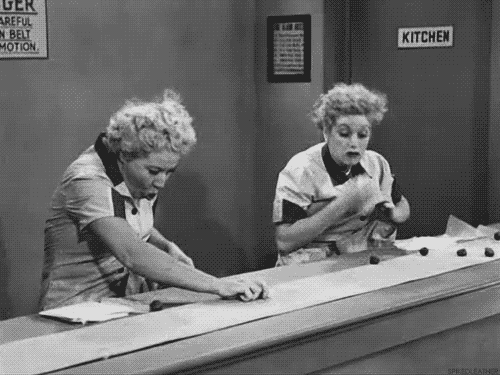 Lucy and Ethel busily gather chocolate from the assembly line in an episode of I Love Lucy