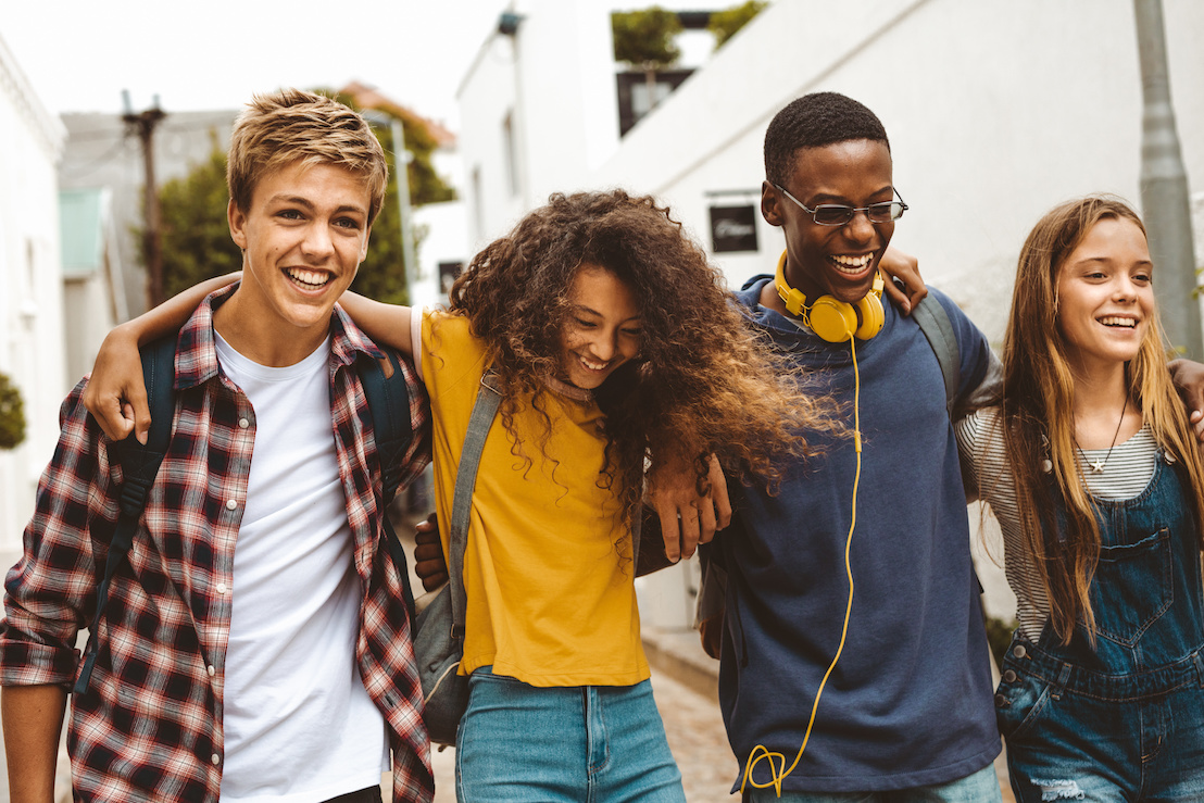 Four friends walking, smiling, and laughing together