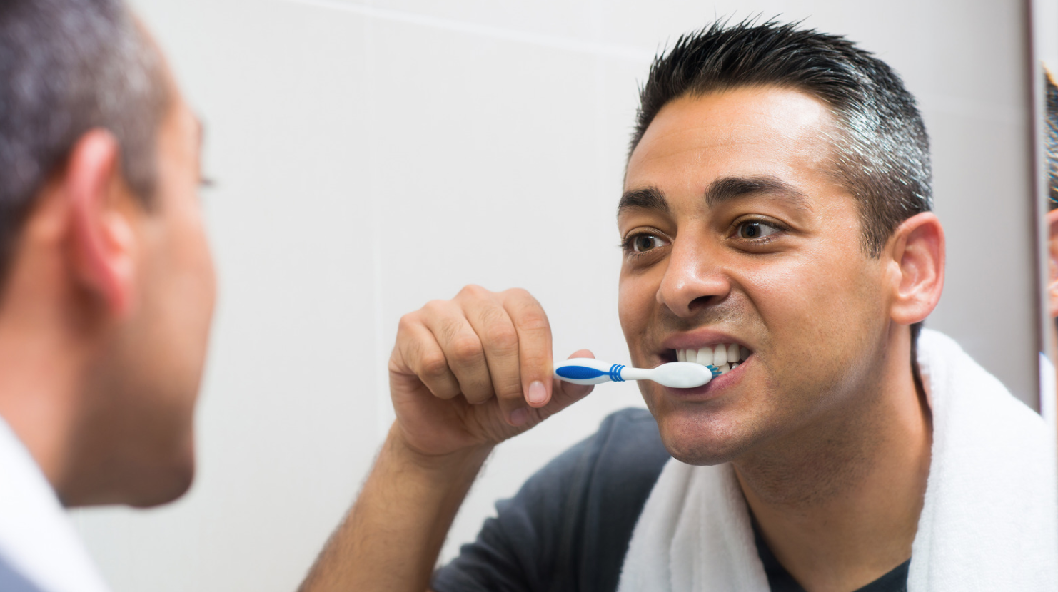man brushing teeth in mirror
