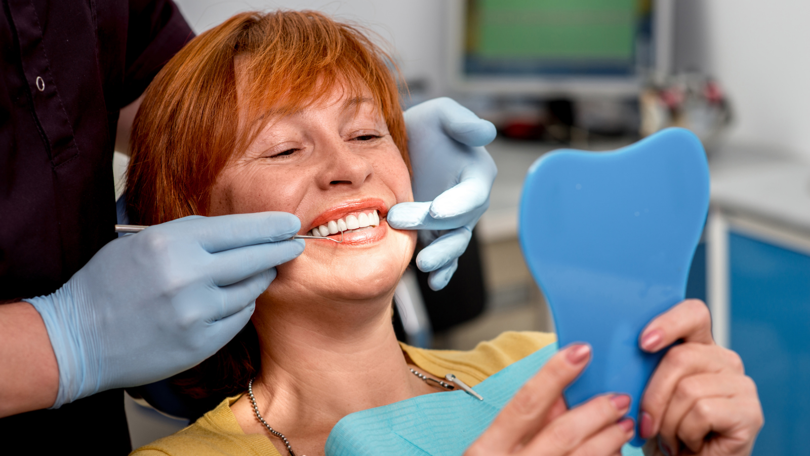 woman checking dentures in dentists office