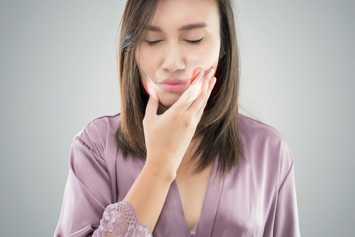 woman holding her jaw in pain
