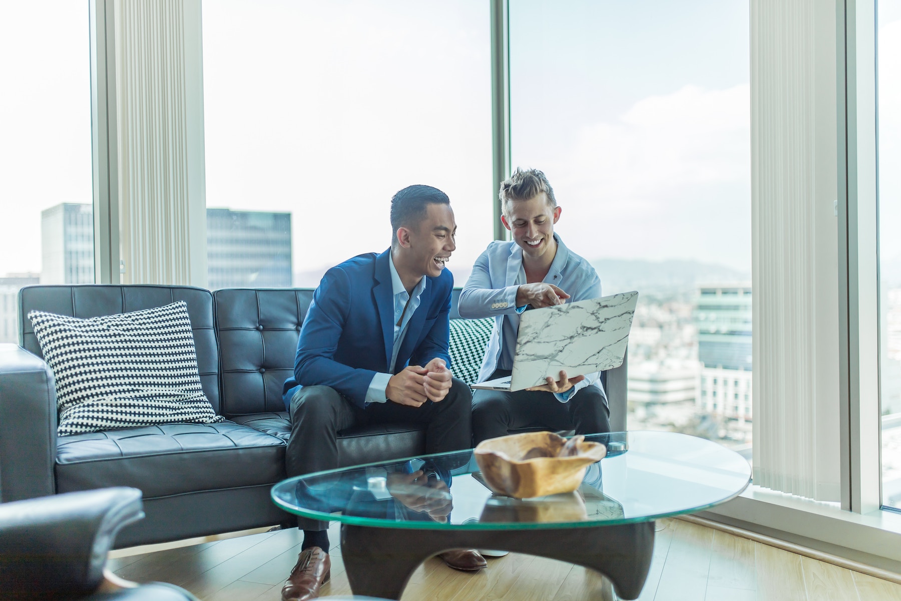 Two business people with laptop, smiling.