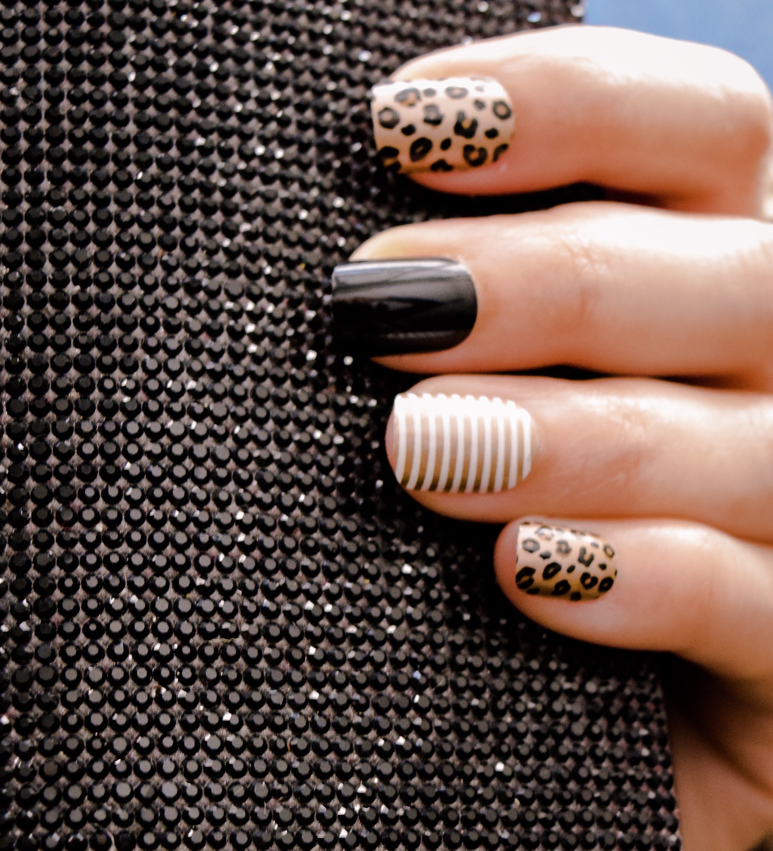 Two manicured hands holding flowers with navy blue nail polish and coral nail design.