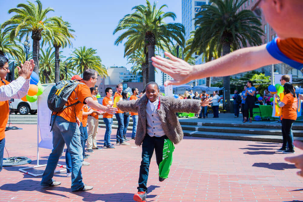 Happy boy running along row of people offering high fives