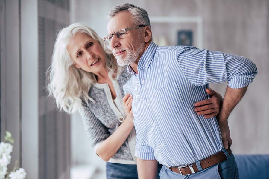 man with back pain being helped by woman