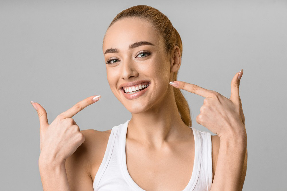 woman smiling and pointing at her teeth