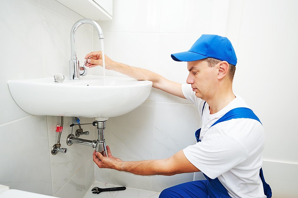 Plumber checking sink tap.