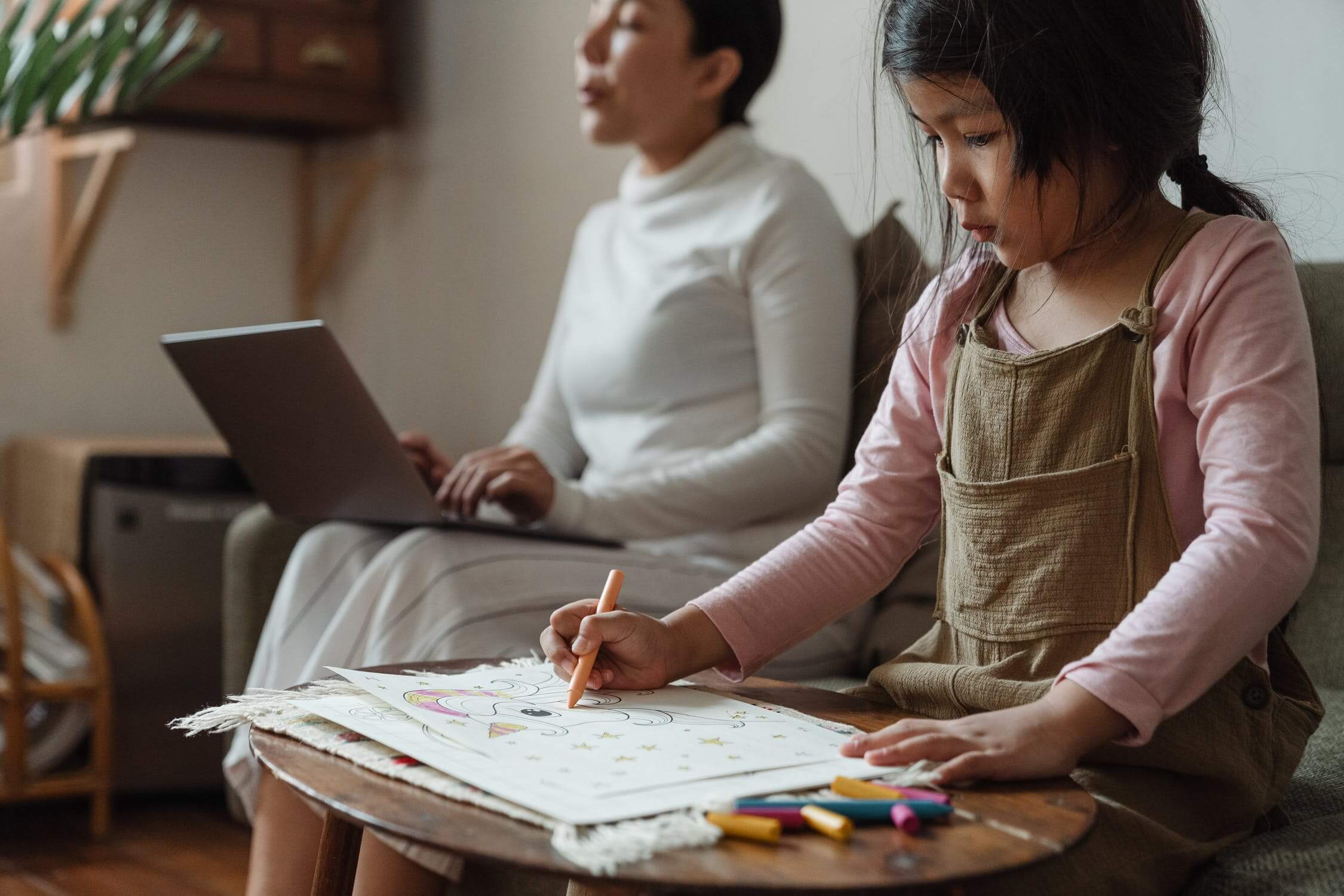 Mom working while child colors.