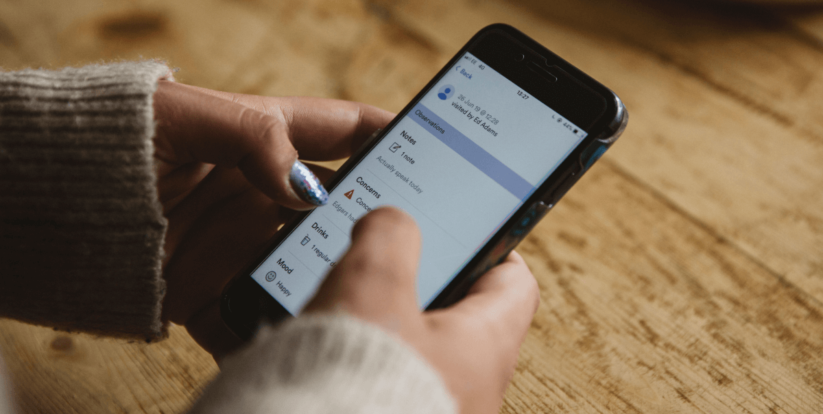 carer uses Birdie on smartphone at wooden table