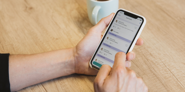 Person holding a phone using Birdie on a wooden table with a cup of tea in the background