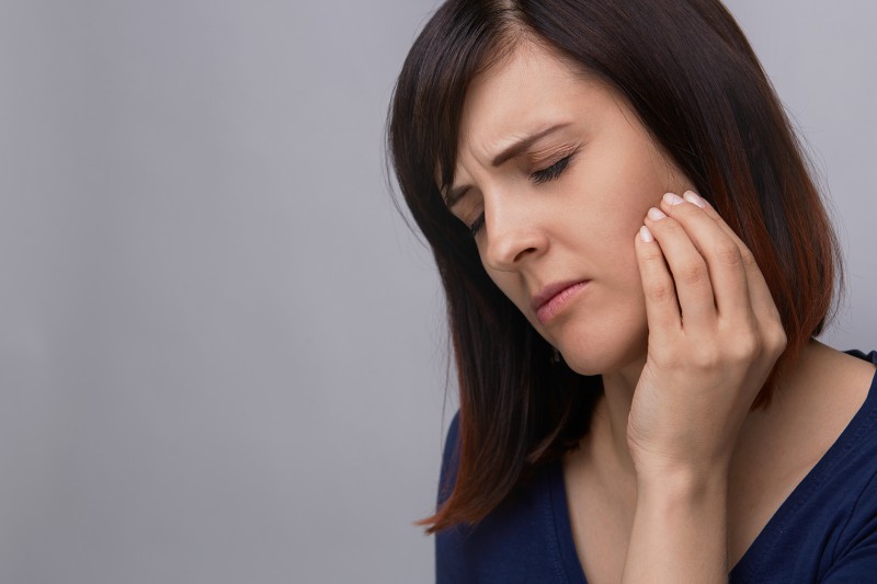 woman holding jaw in pain