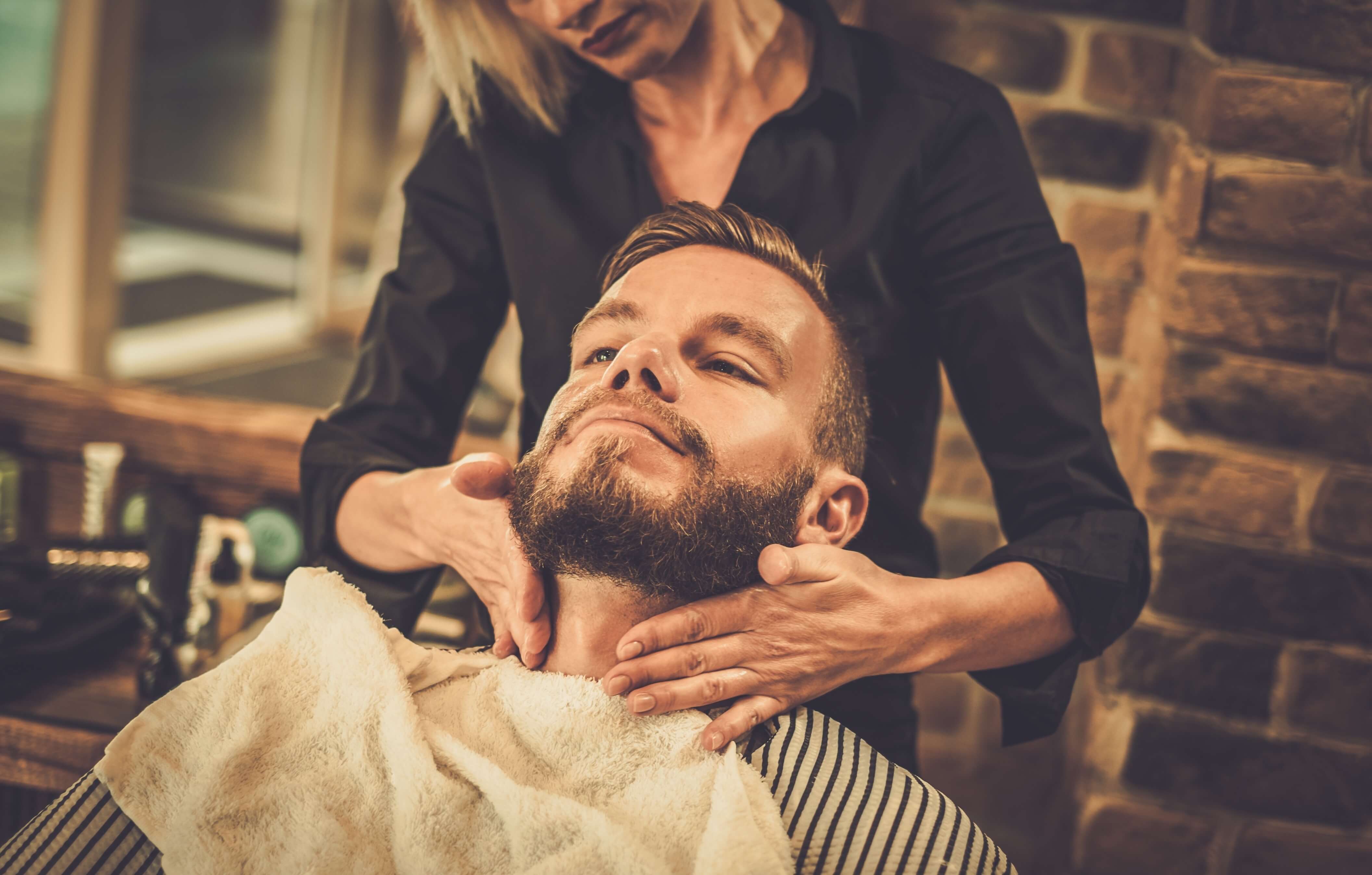 A man getting his beard groomedby a woman.