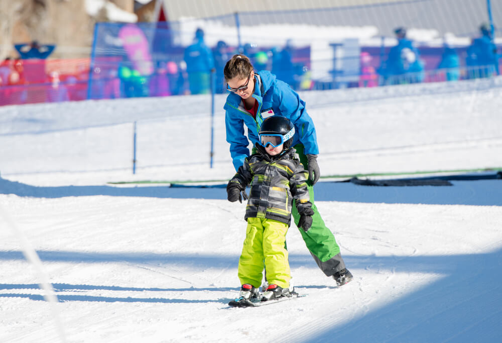 A young boy taking a ski lesson.